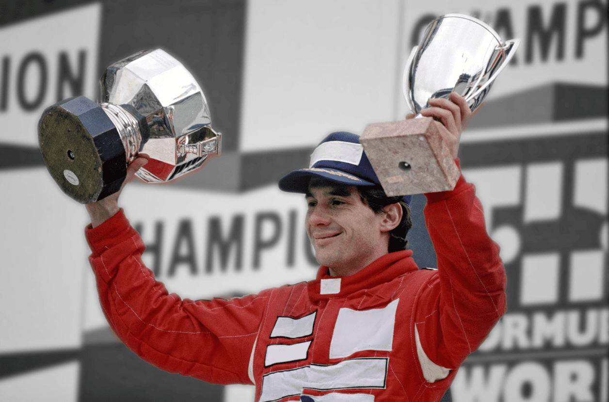 Ayrton Senna holding trophies on the podium